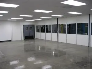 Large empty cleanroom with bright overhead lighting, epoxy flooring, and double doors